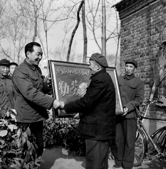1978年，黨的十一屆三中全會召開，做出了對于當代中國發展具有歷史性影響的重大決策，開啟了改革開放和集中力量進行社會主義現代化建設的歷史新時期。圖為1982年，時任河南省鄢陵縣縣長吳德榮上門為該縣第一個“萬元戶”頒發勞動光榮匾。